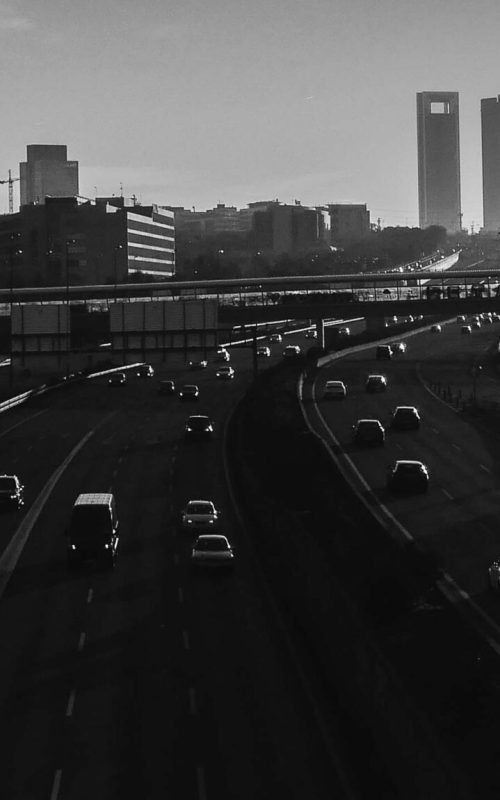 A high angle greyscale shot of a highway with many cars in Madrid, Spain
